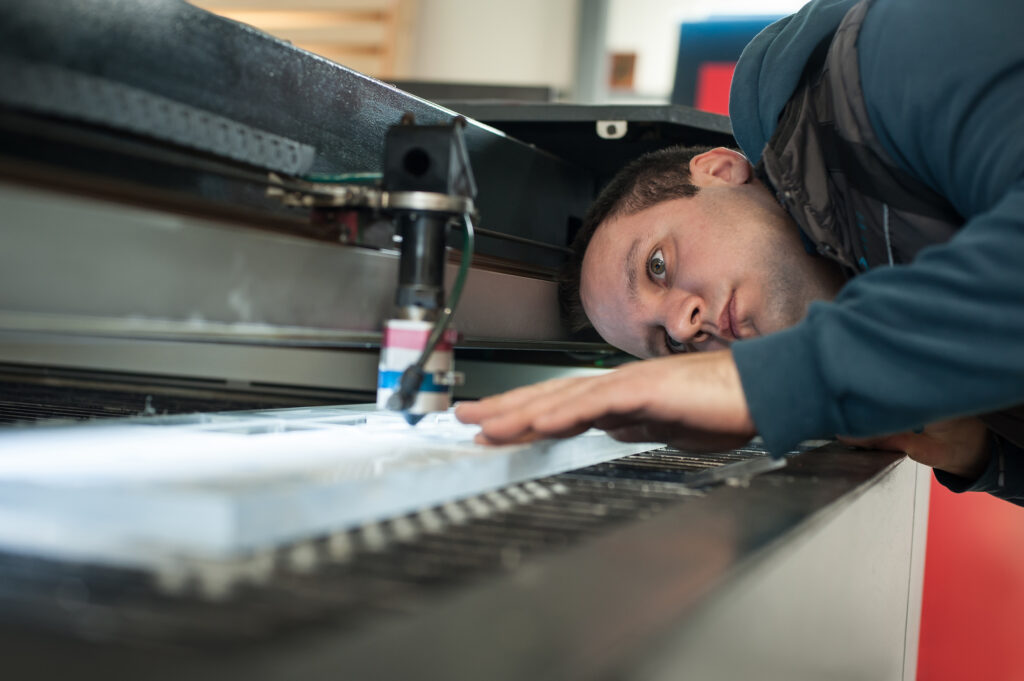 engineer working on laser cutting machine making sure that there are no errors