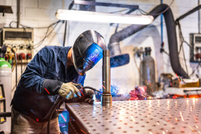 metal welding - working wearing safety gear and welding a metal pipe 